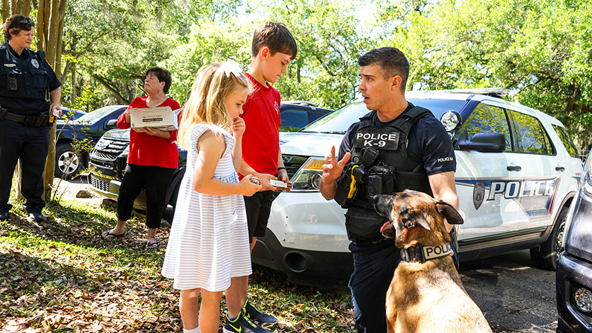 An officer with a K9 talks to children